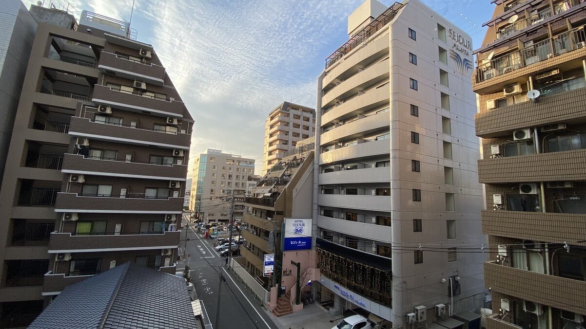 A multi-story hotel with balconies, a sign for 'Hotel Sejdur Plaza,' and a street view.