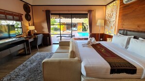 A hotel room with a bed, a desk, a chair, a TV, and a view of a pool. - Naga Tara Resort (Phayao)