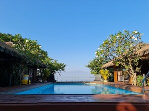 A swimming pool with a view of the sea and mountains in the distance.