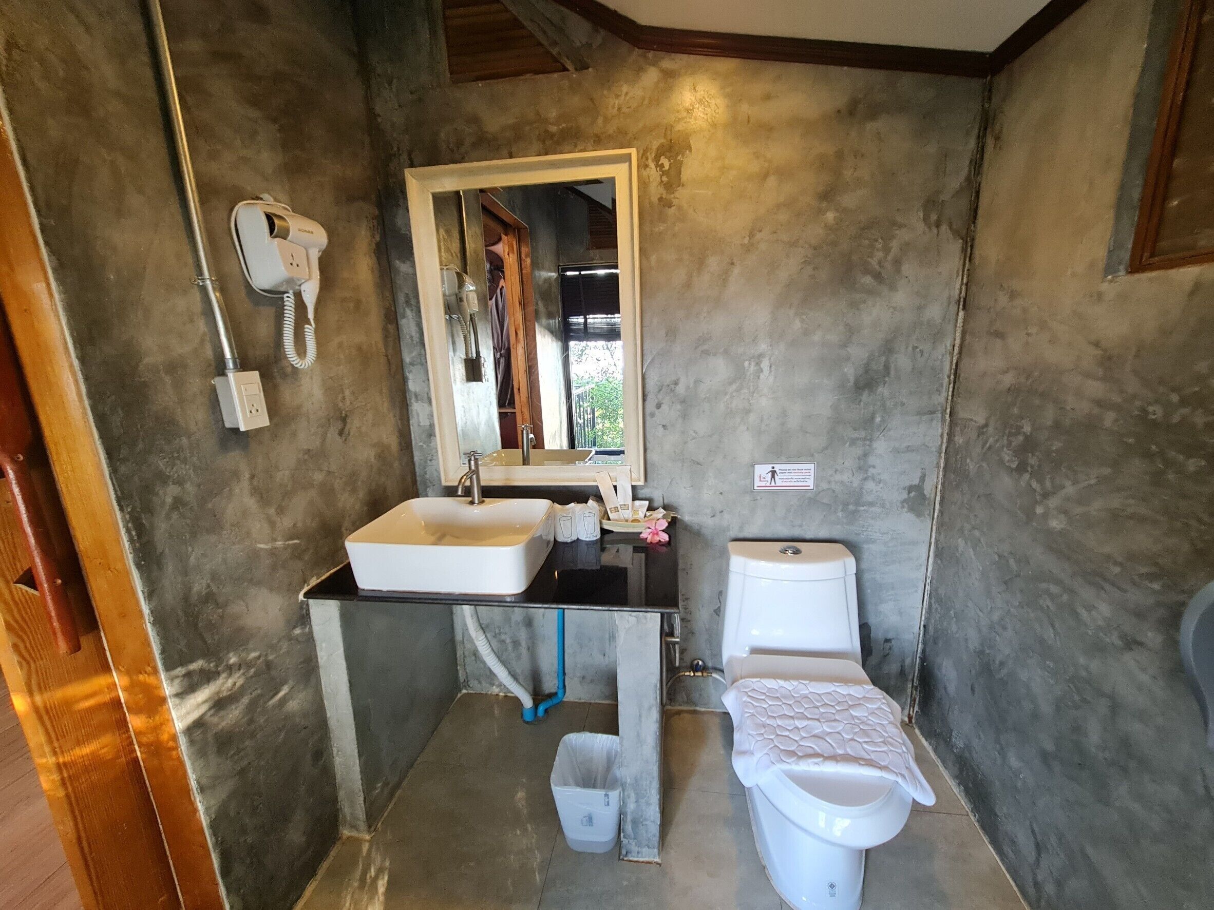 Een badkamer met een wit wastafel, toilet en een haardroger aan de muur.