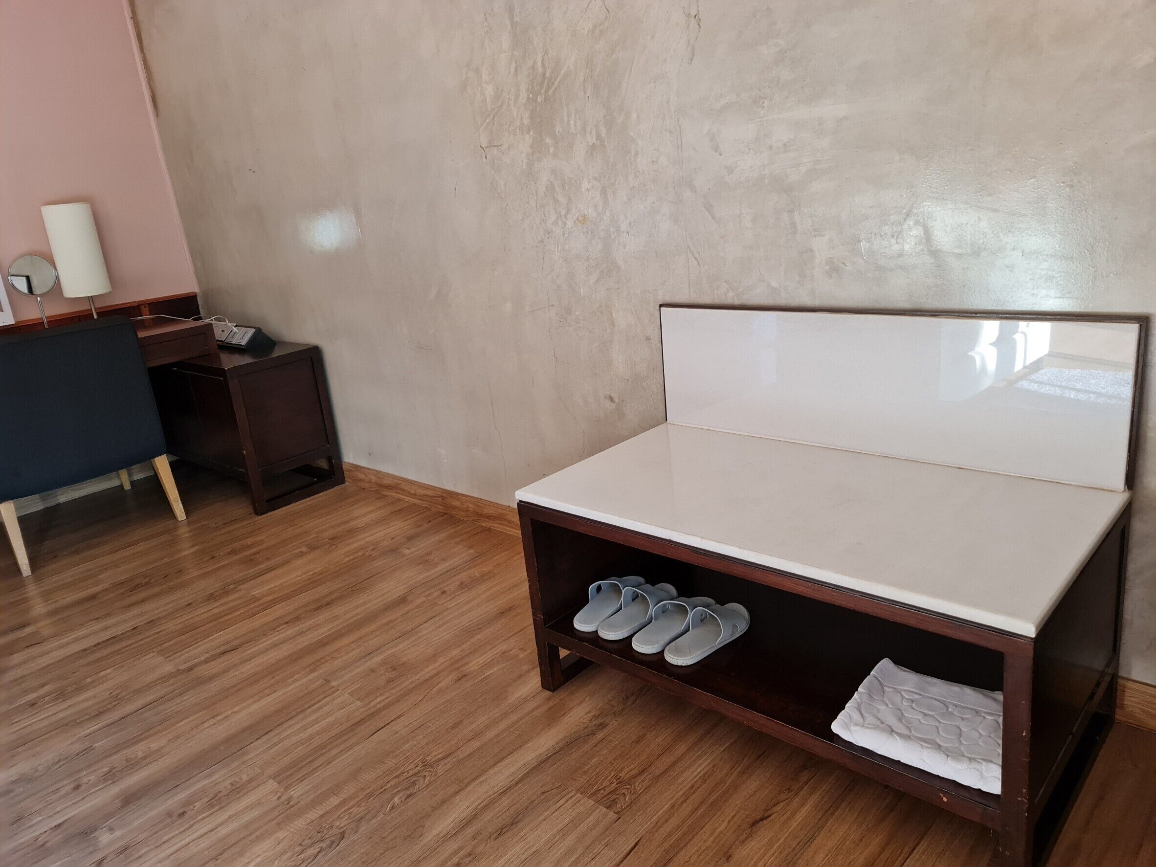 A bedroom with a bed, a desk, and a shoe rack.