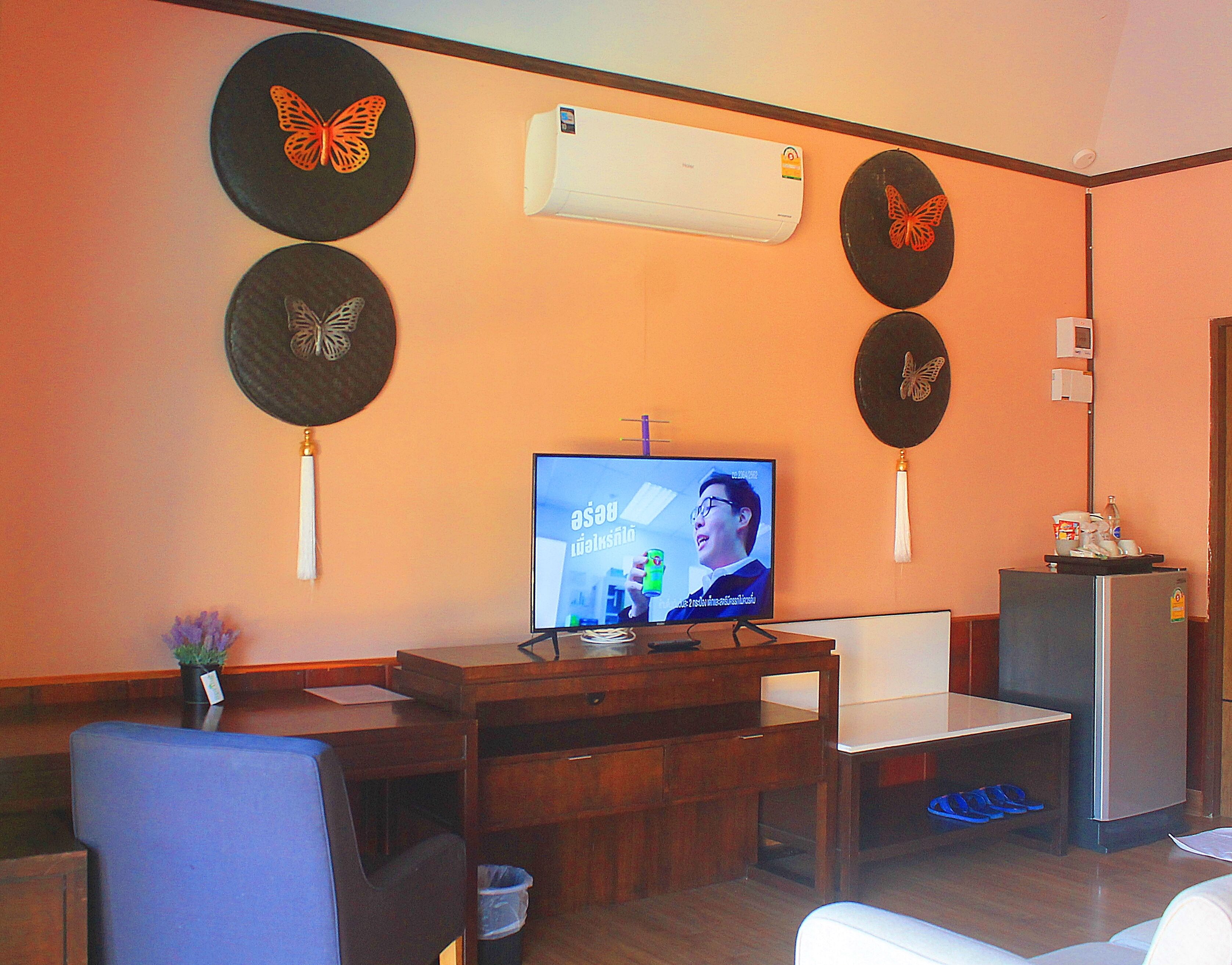 A living room with a TV, wooden furniture, and decorative butterfly wall hangings.
