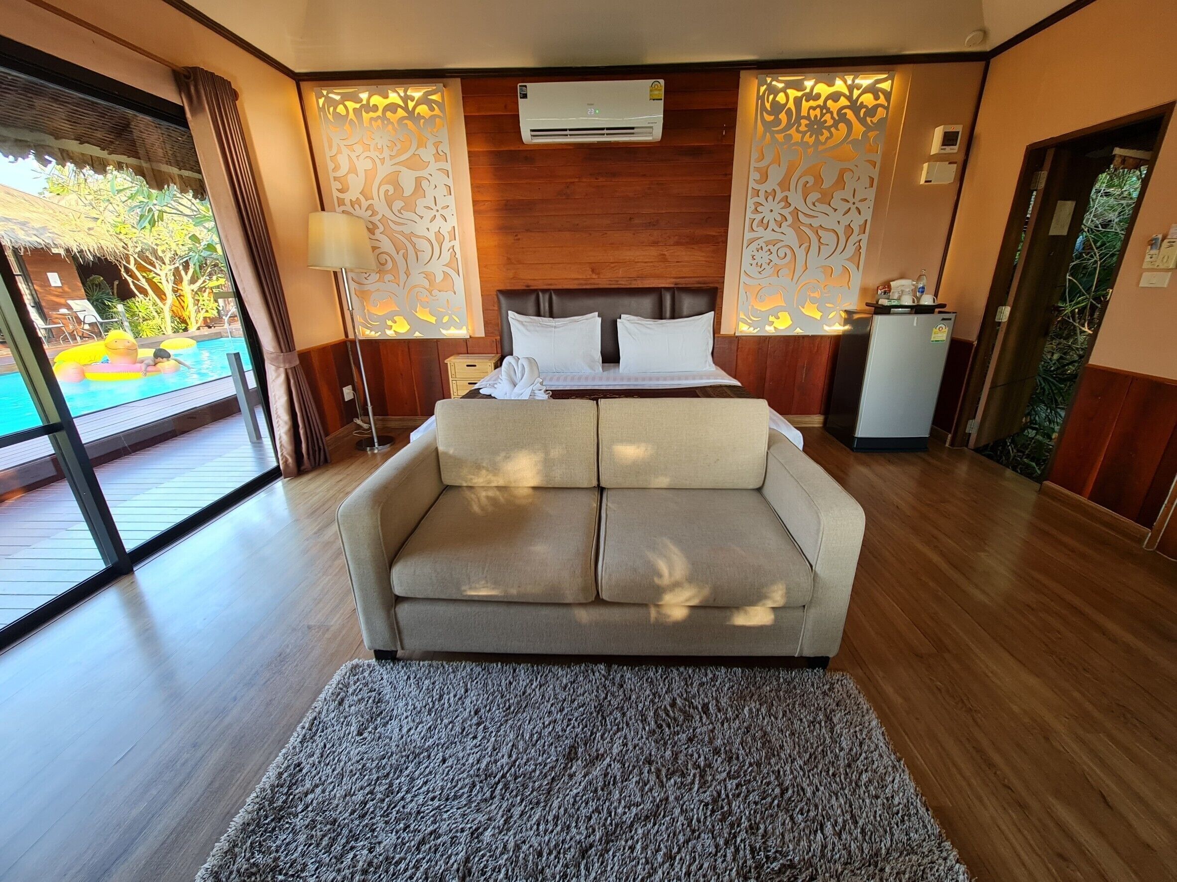 Un dormitorio con cama, sofá, escritorio y vista a una piscina exterior.