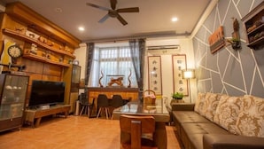 A modern living room with a TV, wooden shelves, a dining table, and a sofa. - A Xin B&B (Jinning)