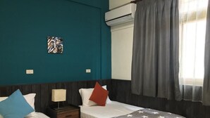 A hotel room with two beds, a nightstand, a lamp, a wall-mounted air conditioner, and a window with curtains. - A Xin B&B (Jinning)