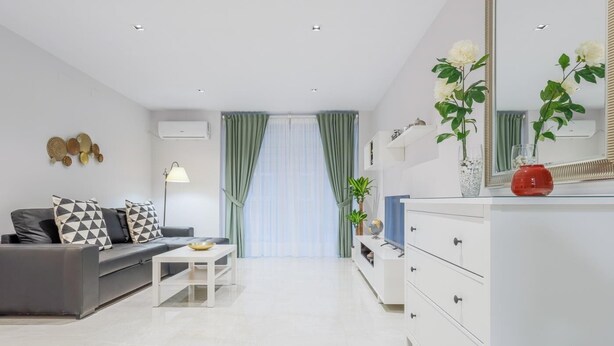Un salon moderne avec un canapé gris, une table basse blanche et une commode blanche dotée de tiroirs.