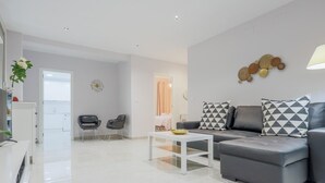Un salon moderne avec un canapé gris, deux fauteuils, une table basse blanche et un élément décoratif mural.