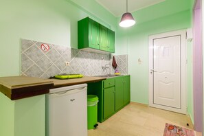 A kitchen with green cabinets, a white refrigerator, and a tiled backsplash.