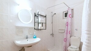 A bathroom with a sink, toilet, shower, and a towel rack. - Ni-Mar Studios & Apartments (Zakynthos)