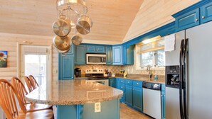 Una cocina con armarios azules, encimera de granito, refrigerador de acero inoxidable y microondas integrado.