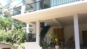 A two-story building with a balcony, a staircase, and potted plants. - Misty Elegance Ella (Ella)