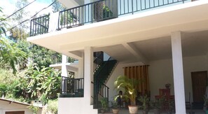 A two-story building with a balcony, a staircase, and potted plants. - Misty Elegance Ella (Ella)