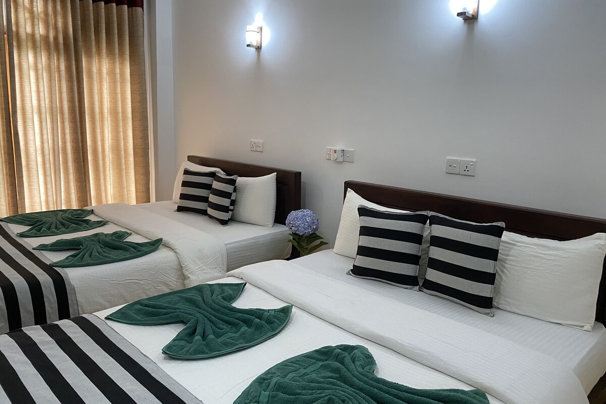 A hotel room with two beds, each with striped bedding and green towels.