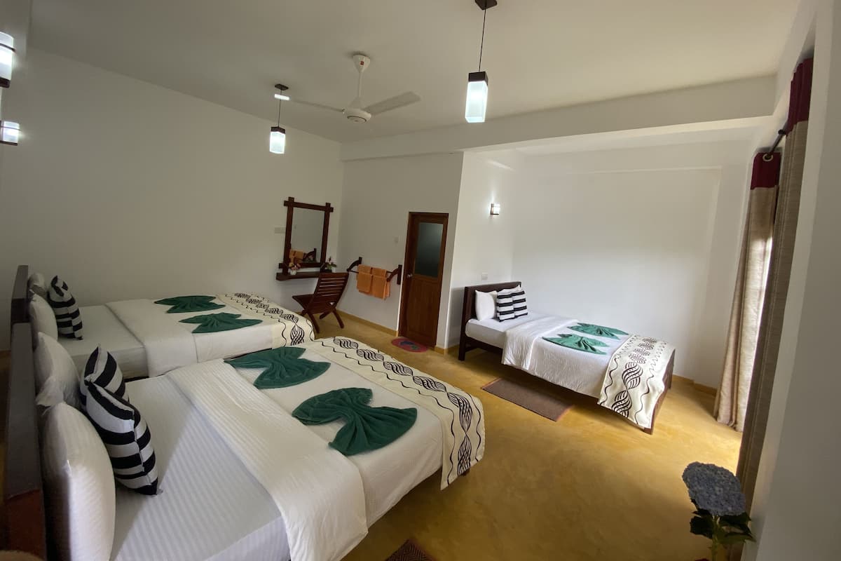 Habitación de hotel con dos camas, ventilador de techo, espejo y una mesita.