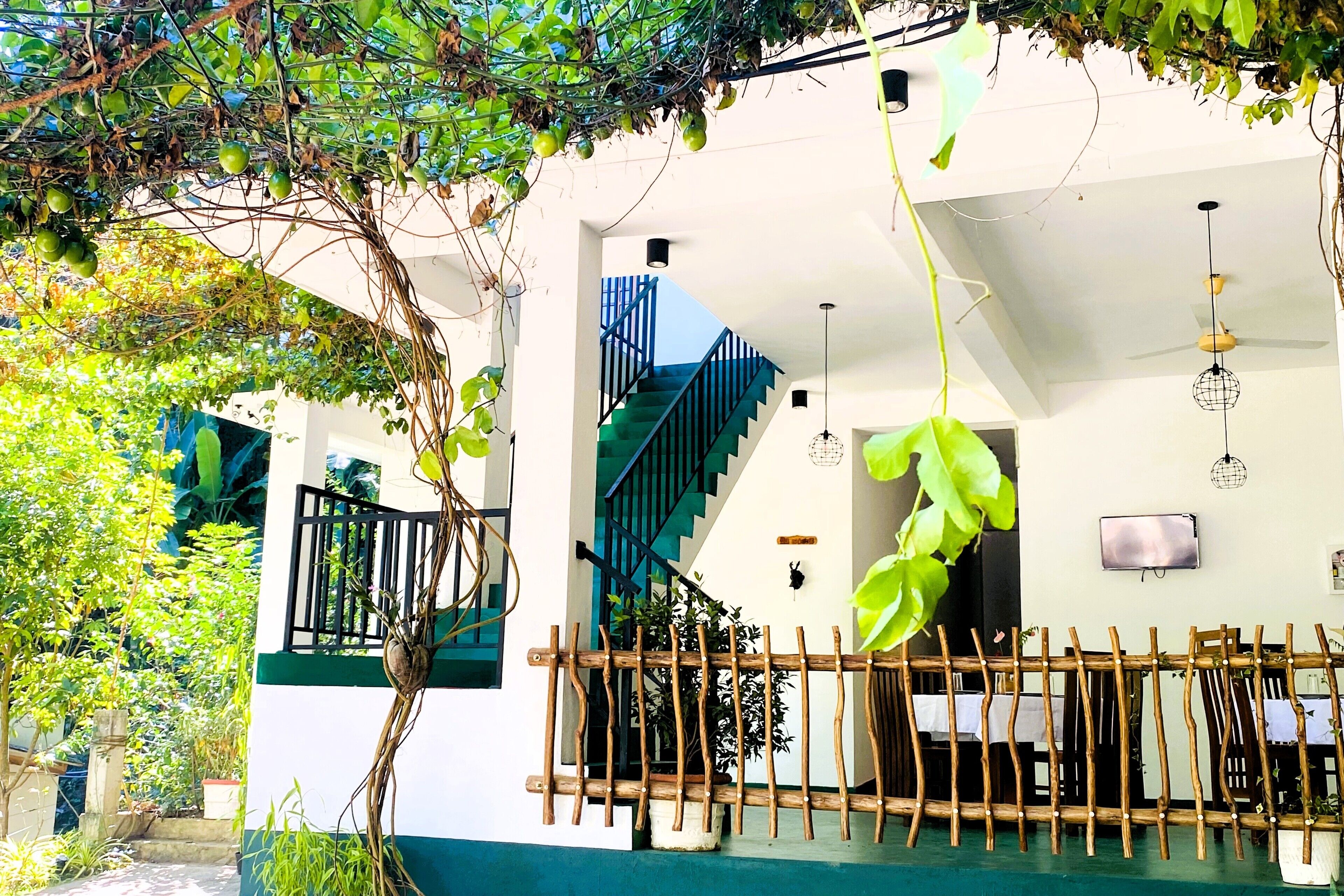 A house with a staircase, a hanging plant, and a fence.