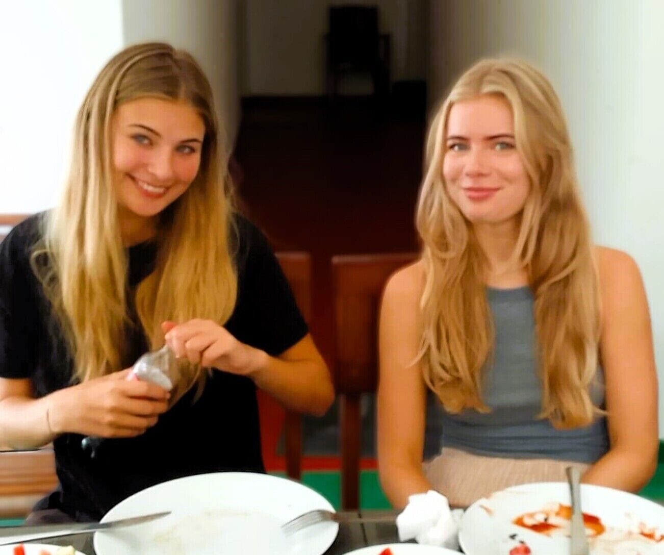 Dos personas sentadas a una mesa con platos y cubiertos, indicando un ambiente para comer.