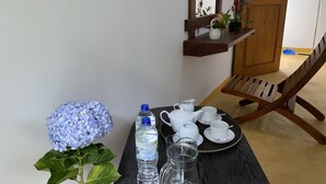 A table with a water bottle, teapot, cups, and saucers, a potted plant, and a blue hydrangea. - Misty Elegance Ella (Ella)