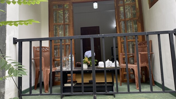 A balcony with a table set for tea, surrounded by wooden chairs, and a railing. - Misty Elegance Ella (Ella)