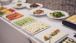 A buffet with various food items including sliced cucumbers, eggs, and salads. - Marina Apartments (Wroclaw)