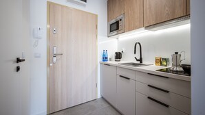 A modern kitchen with wooden cabinets, a microwave, a kettle, and a coffee maker on the countertop. - Marina Apartments (Wroclaw)