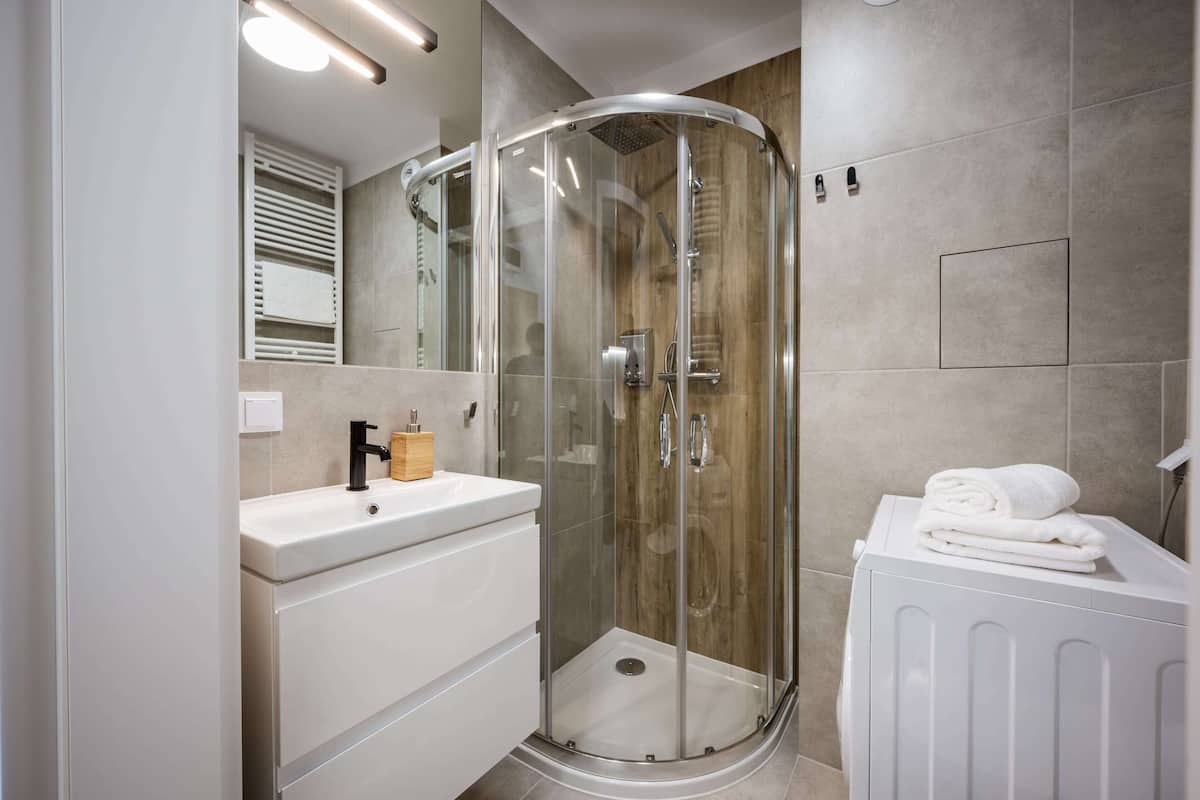 A modern bathroom with a glass-enclosed shower, a white vanity with a sink, and a radiator.