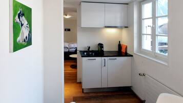 Una cocina moderna con armarios blancos, una cafetera y un ventanal.