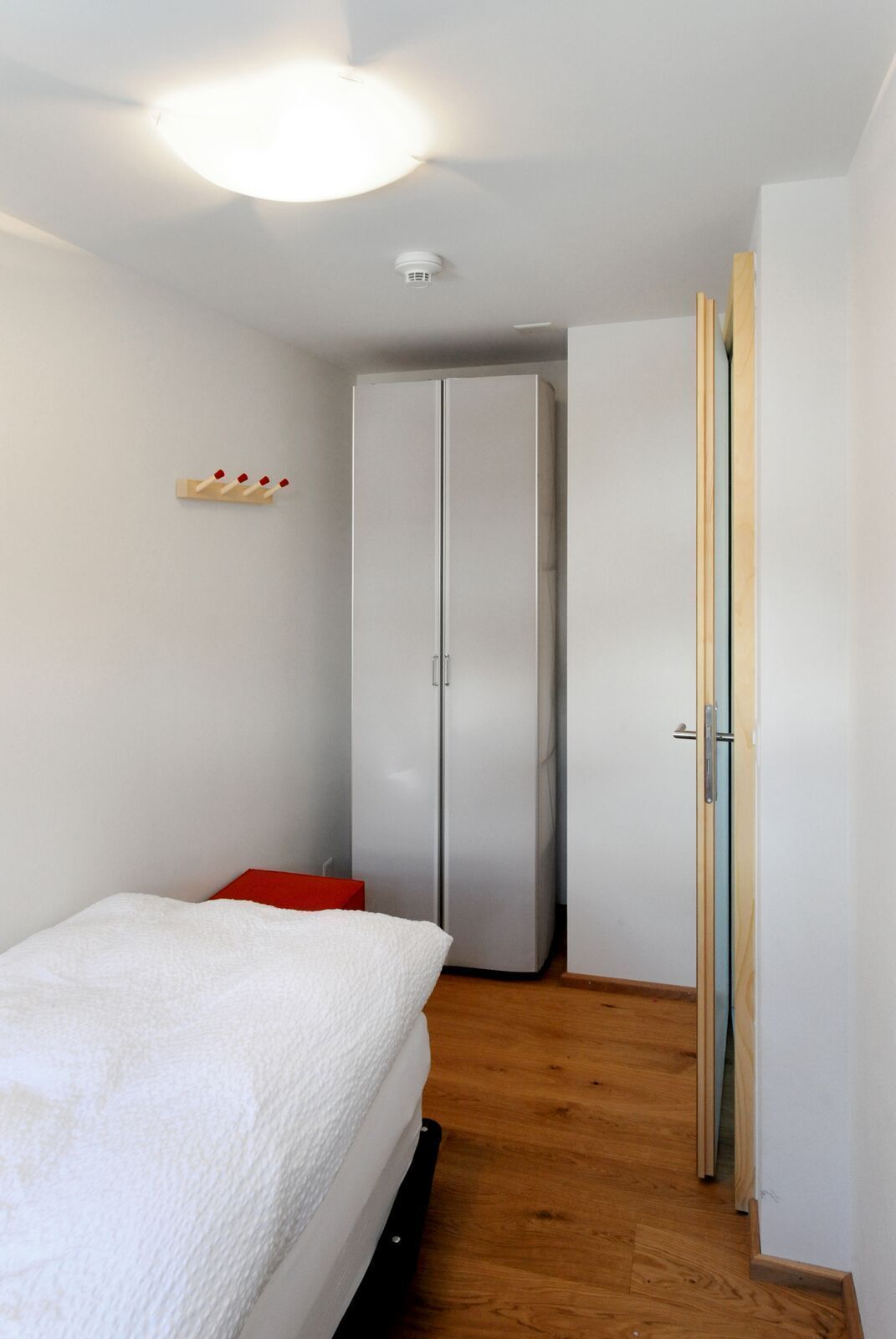 A bedroom with a bed, a wardrobe, and a door.
