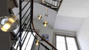 Una escalera con barandilla de metal y lámparas colgantes.
