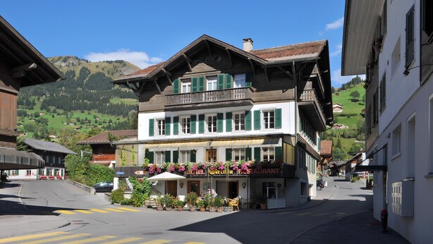 Un hotel con balcón, un letrero de restaurante y vistas a las montañas.