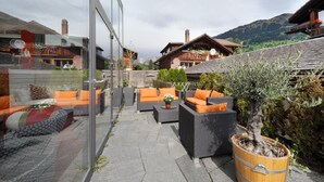 Un patio con mobiliario exterior, un árbol en maceta y vistas a la montaña.