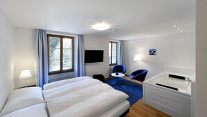 Habitación de hotel con una cama grande, un escritorio, una silla, un televisor y una bañera.