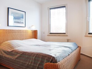 Ein Schlafzimmer mit einem Bett, einem gerahmten Bild an der Wand und einem Fenster mit Jalousien.