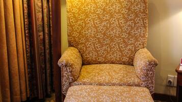 A chair with a patterned fabric, a floor lamp, and curtains in a room.