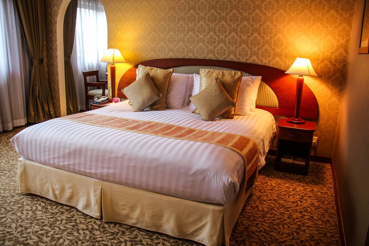 A hotel room with a large bed, two bedside tables, a nightstand, and a chair.