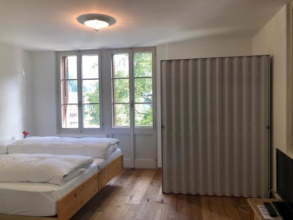 Une chambre avec deux lits, une fenêtre, un rideau et un bureau avec un ordinateur.