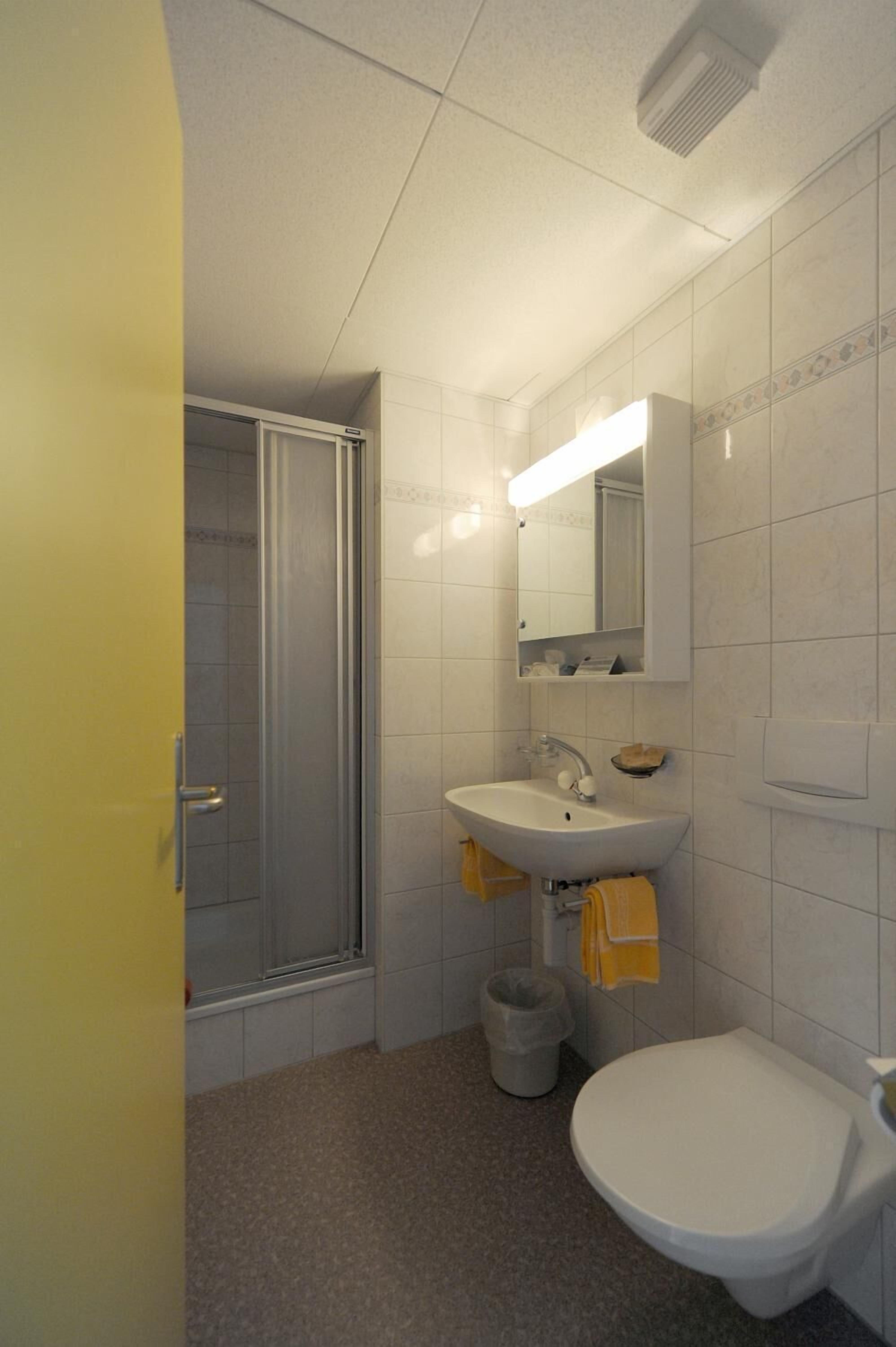 Un baño pequeño con ducha, lavabo e inodoro.