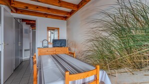 A room with a bed, a wooden dresser, a television, and a large plant. - Spacious Duplex for 6, 300m from Ocean, 2 Bedrooms, South Balcony (Biscarrosse Plage)