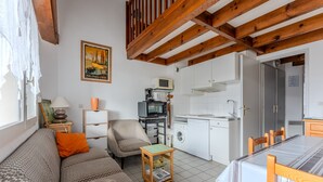 A compact living space with a sofa, a small table, a kitchen area with appliances, and a dining table. - Spacious Duplex for 6, 300m from Ocean, 2 Bedrooms, South Balcony (Biscarrosse Plage)