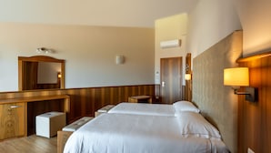 A hotel room with a wooden desk, a bed with white linens, a bedside table, and a wall-mounted lamp. - Hotel Centrale (Garda)