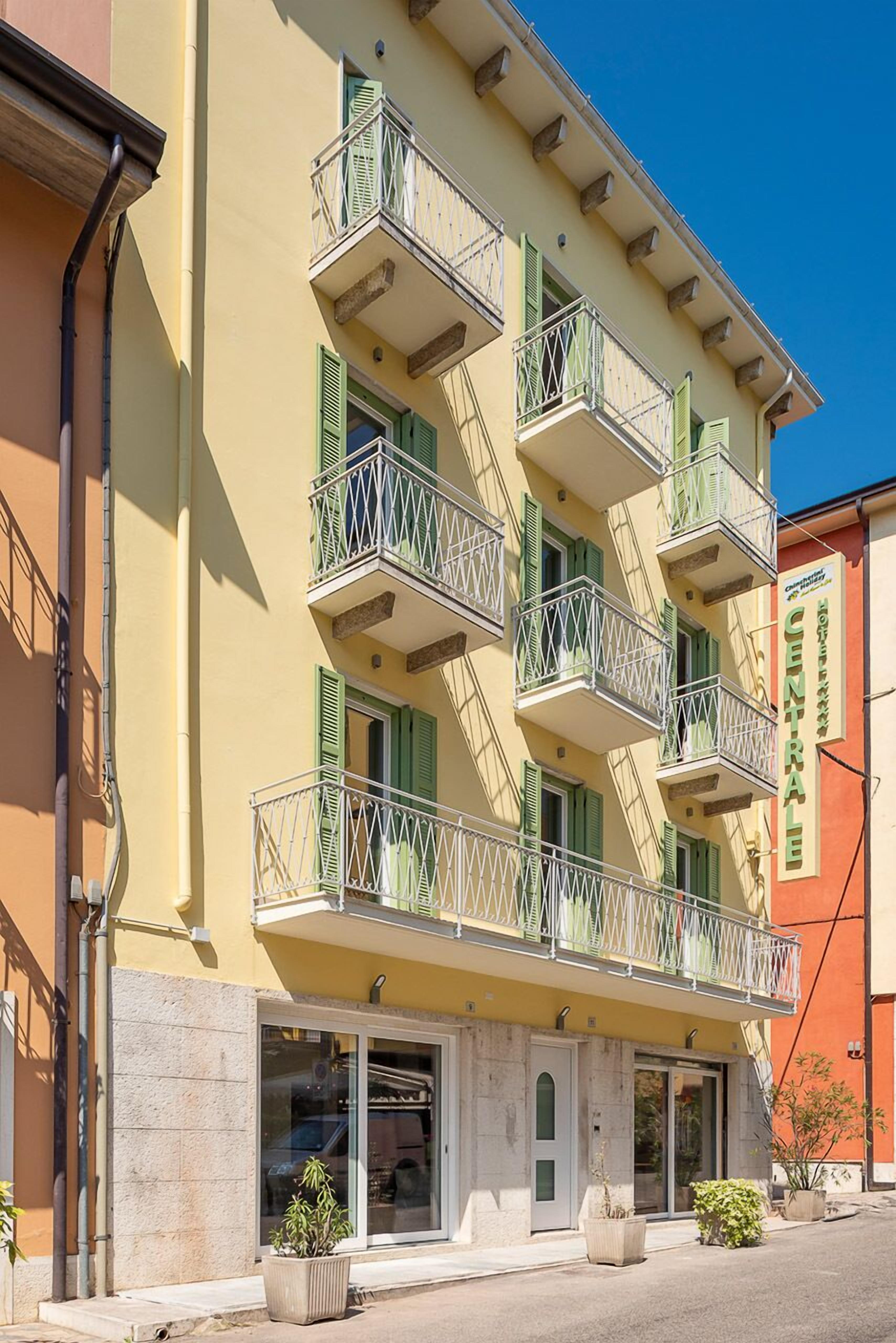 A multi-story hotel with balconies, a central entrance, and a sign indicating it is a hotel.