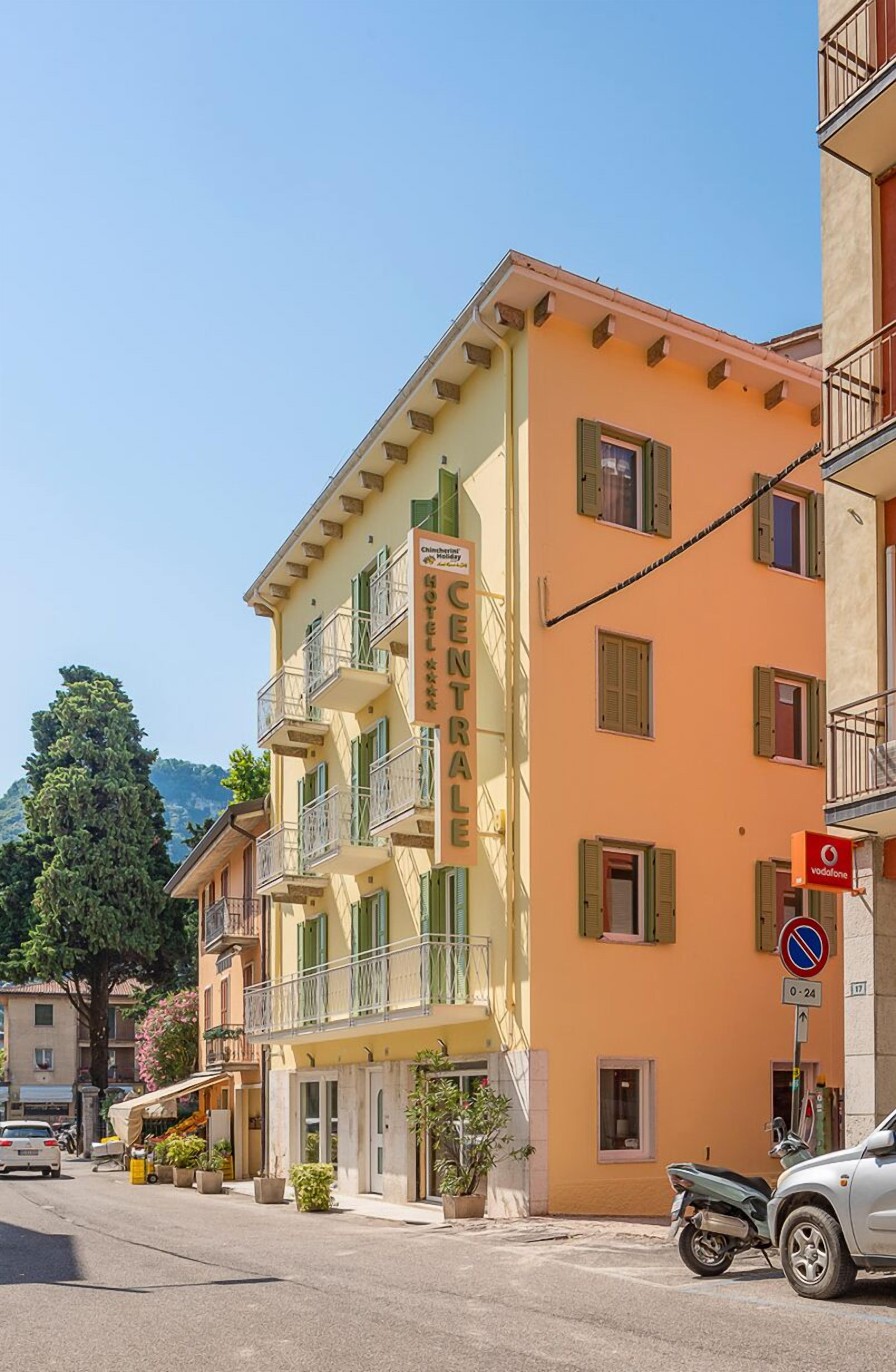 Un hotel chiamato "CENTRAL" con facciata gialla, balconi e cielo sereno.