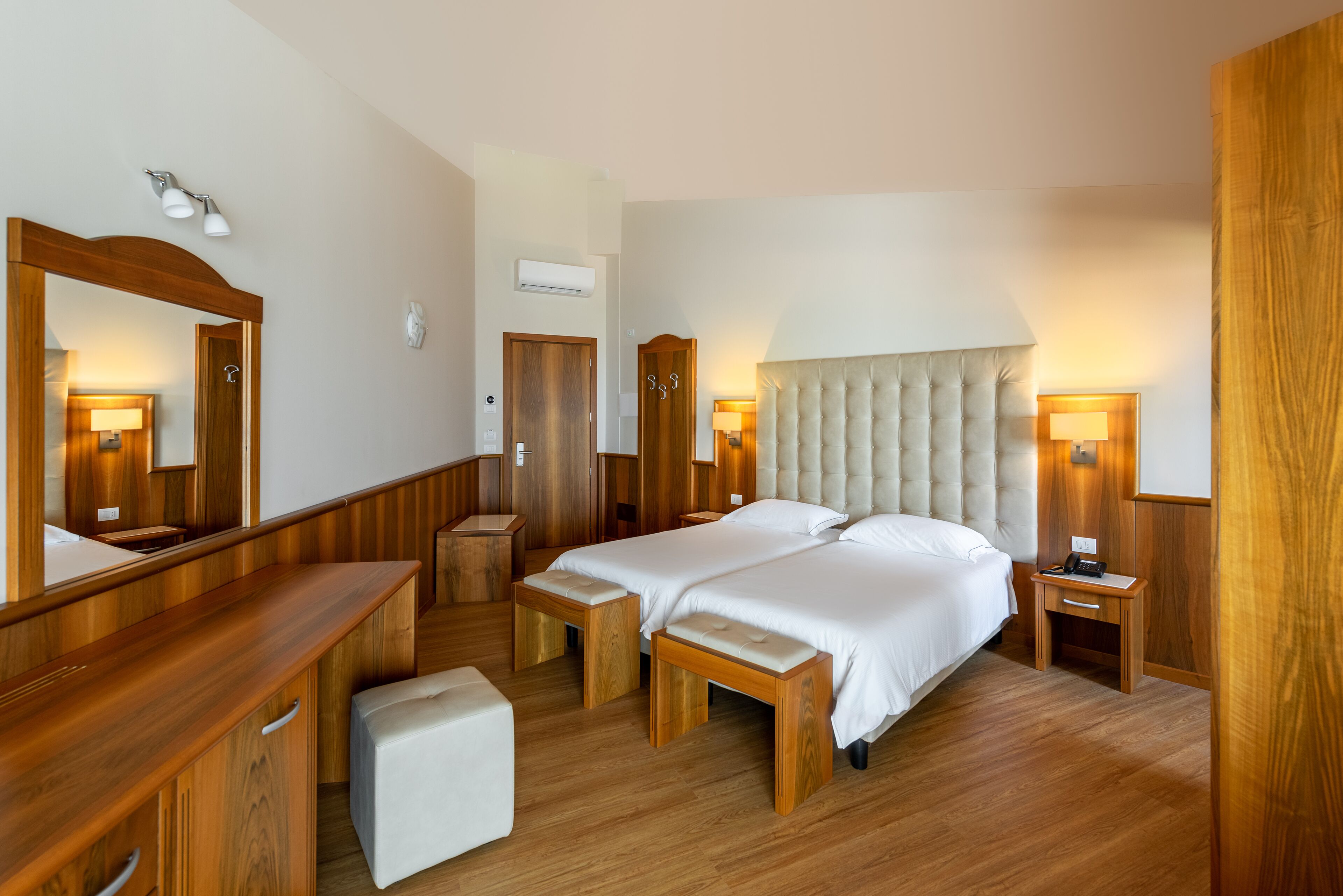 Habitación de hotel con dos camas, muebles de madera y un espejo grande.