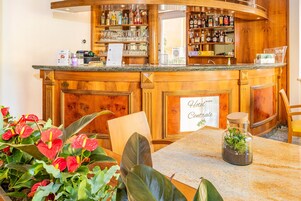 Un bar de hotel con decoración de madera, un cartel que dice 'Hotel Centrale' y una mesa con un jarrón de flores.