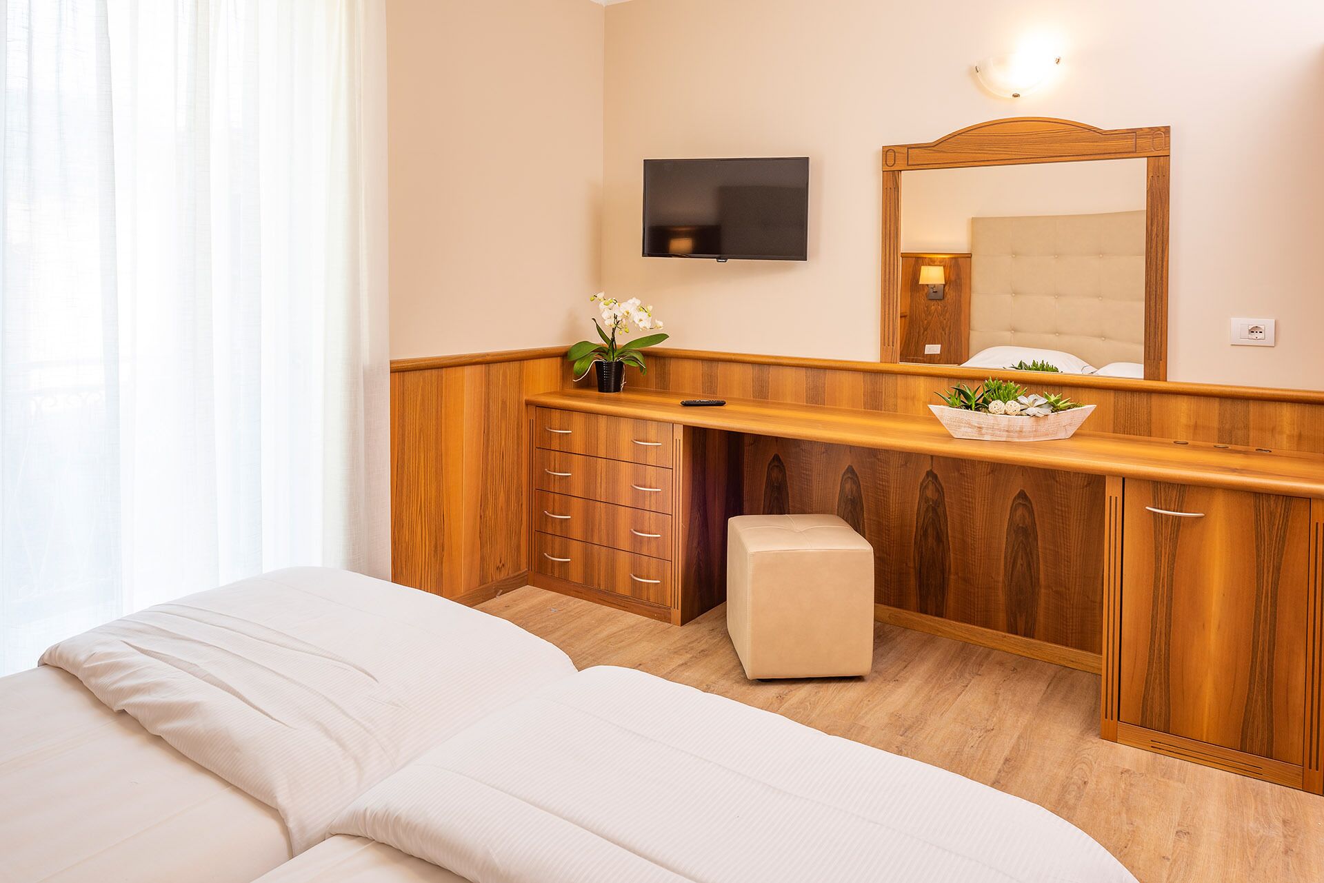 Ein Hotelzimmer mit einem Holznäpfchen, einem Bett, einem Fernseher und einem Spiegel.