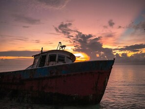 Ein Boot mit Kabine und Deck liegt bei Sonnenuntergang in ruhigem Wasser vor Anker.
