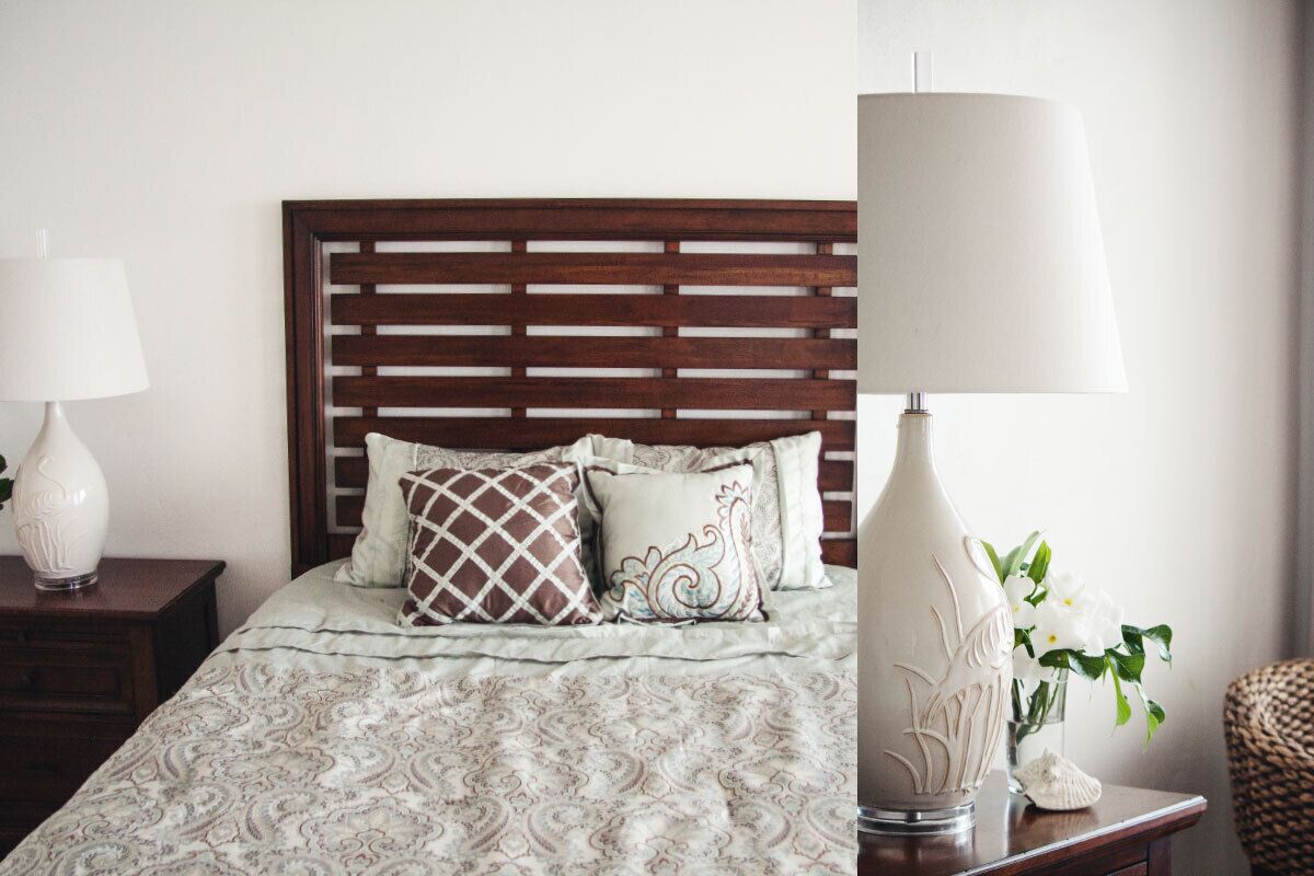 A neatly made bed with patterned bedding, a wooden headboard, and two bedside lamps.
