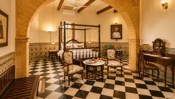 Una habitación con cama con dosel, un escritorio, dos sillas y piso a cuadros.