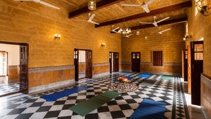 Una habitación amplia con suelo de cuadros, varias puertas y ventiladores de techo.