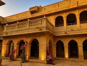 A courtyard with a series of arches and a balcony with intricate carvings. - WelcomHeritage Mohangarh Fort (Jaisalmer)