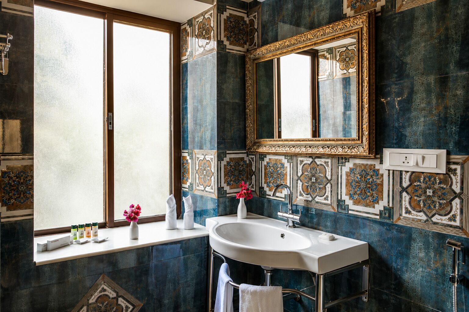 Un baño con un espejo grande, un lavamanos y azulejos decorativos.